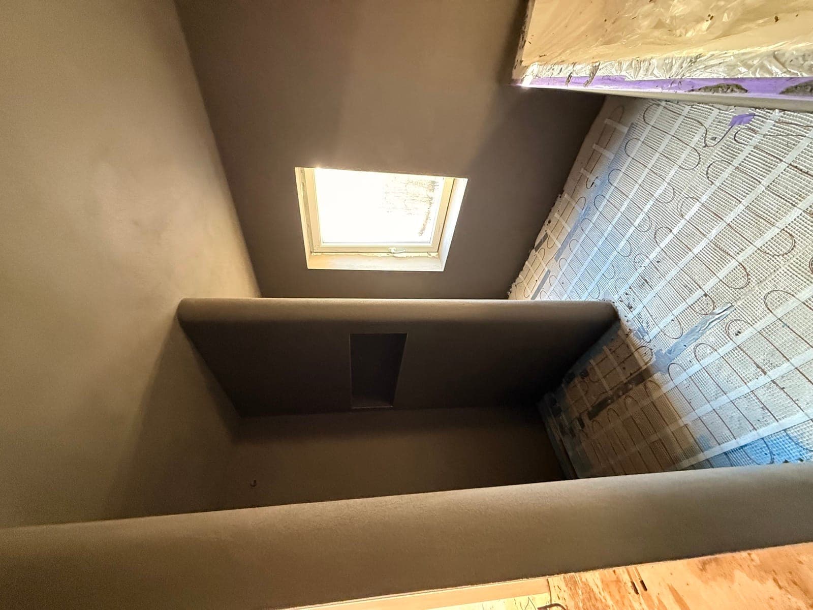 Betonlook badkamer met dakraam en nisjes